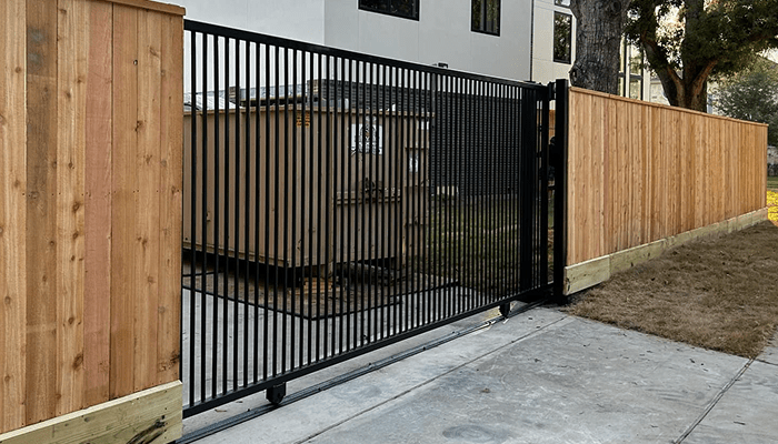 Wrought iron driveway gate with wood fence in houston