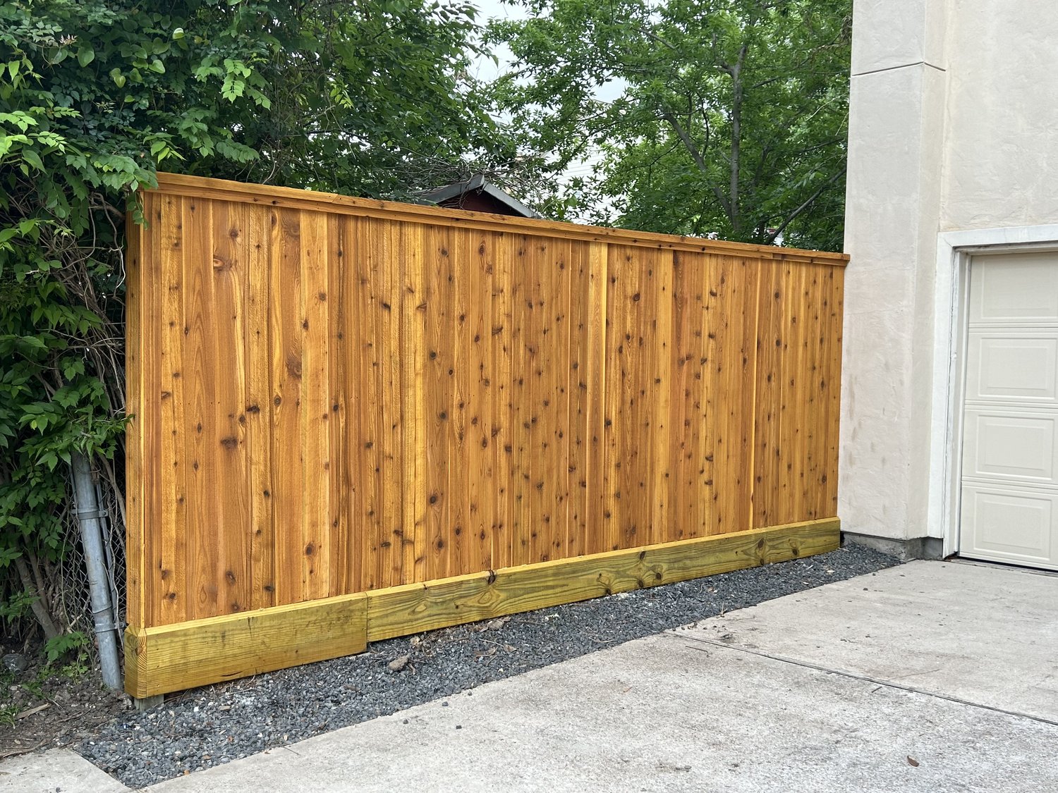 Golden stained board-on-board cedar fence beside a driveway — Jorge Torres Fence, Houston