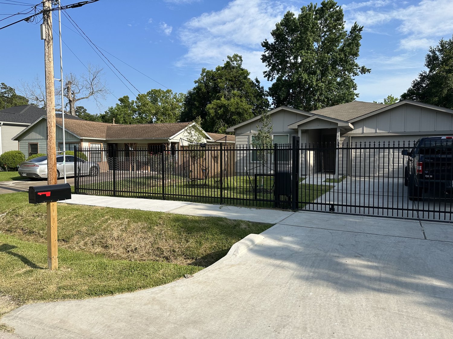 Black wrought iron fence along a front yard driveway — Jorge Torres Fence, Houston